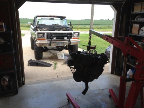 1979 Ford Bronco - An engine is being removed from a Ford truck in a garage, with a field visible in the background.