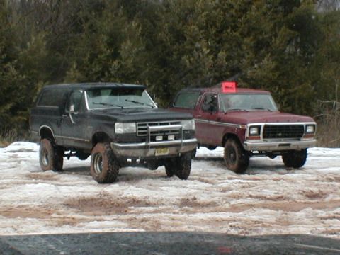 1979 Ford Bronco II - Two Ford Broncos are parked on a wet, snowy surface with trees in the background.