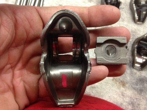 1979 Ford Bronco - Close-up of two metal rocker arms, one being held in a hand, with a red mark on the interior surface of one.