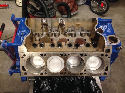 1979 Ford Bronco - A V8 engine block is shown with pistons installed in the cylinders, resting on an engine stand.