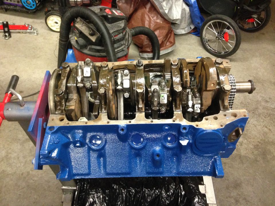 Blue engine block with crankshaft and connecting rods on stand