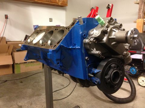 1979 Ford Bronco - Engine block painted blue, mounted on a stand for rebuild. Components like the water pump and pulley are attached.