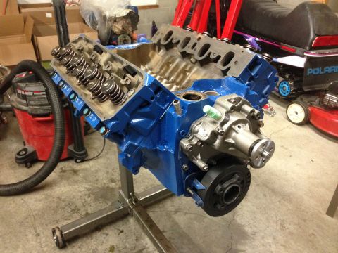 1979 Ford Bronco - V8 engine block, painted blue, sits on a stand in a garage setting.