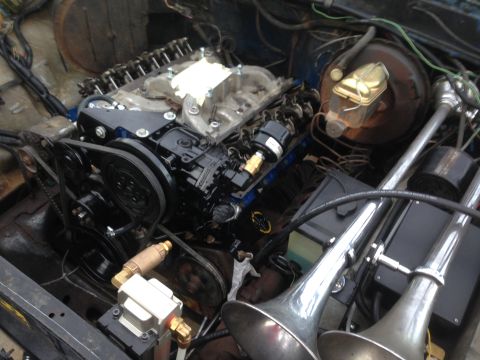 1979 Ford Bronco - Engine bay with V8 engine and custom air horn setup. The engine appears to be undergoing maintenance.