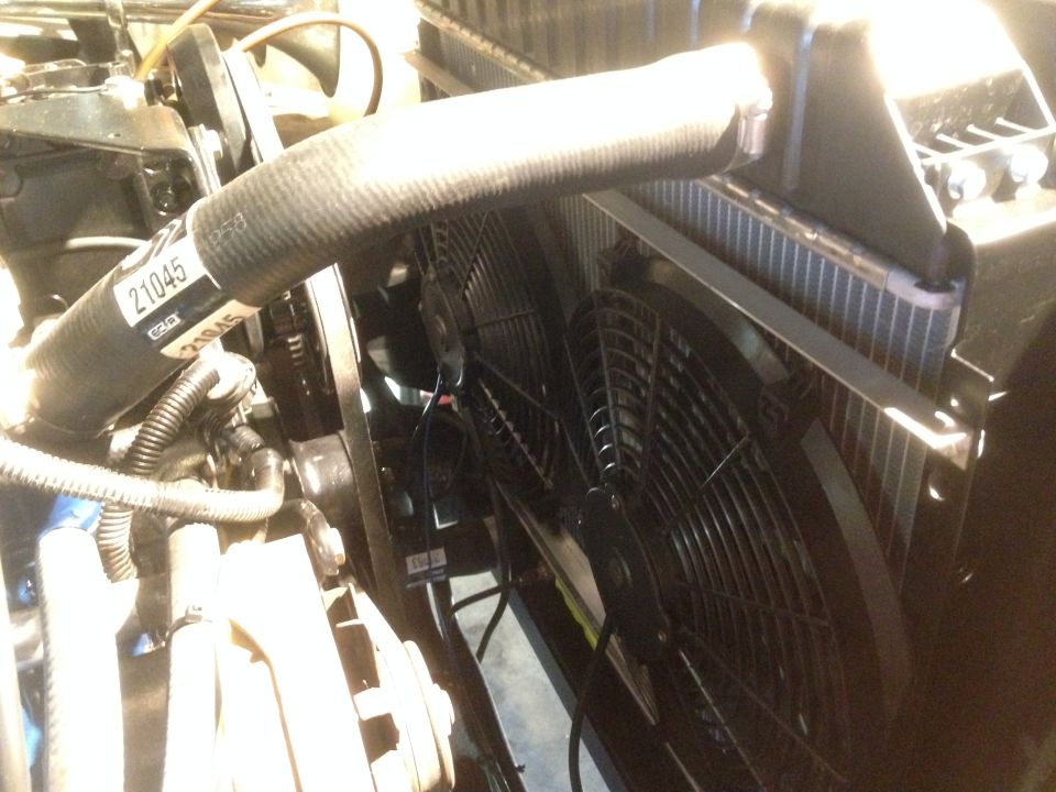 Close-up of engine bay showing radiator, dual electric fans, and a hose with part number 21045