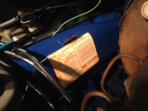1979 Ford Bronco - Close-up of a blue Ford valve cover a 1979 emissions sticker, likely from a Ford Bronco engine rebuild.