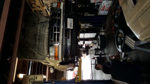 1995 Ford Bronco - A mechanic works on a Ford F-Series truck that is raised on a lift in a repair shop.