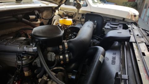 1995 Ford Bronco - Engine bay details of a 1995 Ford Bronco, showing an aftermarket air intake system and other engine components.