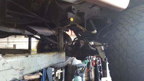 1995 Ford Bronco - Close-up of the rear axle and suspension system of a vehicle, likely undergoing maintenance.