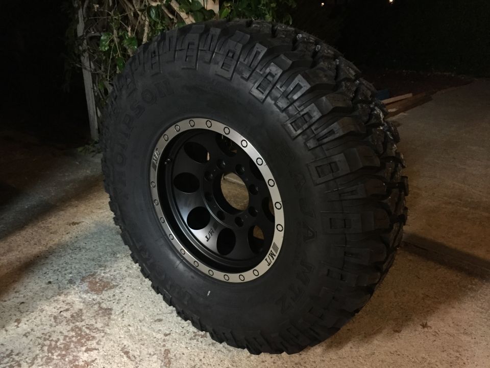 Black off-road wheel with MT tires mounted. Text on tire reads "MUD-TERRAIN T/A"