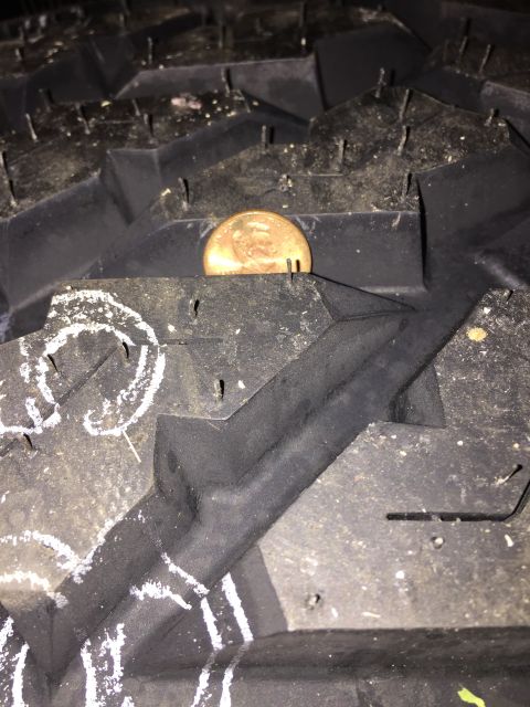 1989 Ford Bronco - A coin is placed in the deep tread of a tire, likely to show tread depth.