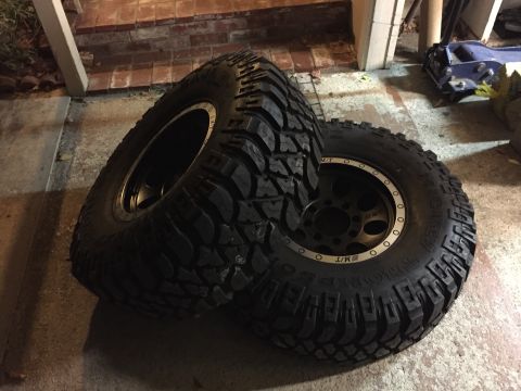 1989 Ford Bronco - A pair of off-road tires with deep treads and black rims are shown, with visible "MT" branding on the sidewall.