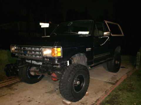 1989 Ford Bronco - This lifted Ford Bronco is parked on a driveway at night, showing off its off-road tires.