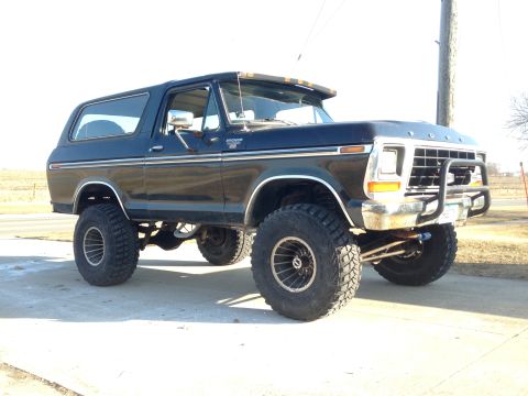 1979 Ford Bronco - Lifted 1979 Ford Bronco with large off-road tires shown from the front 3/4 angle.