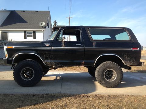 1979 Ford Bronco - Side view of a black Ford Bronco with aftermarket wheels and off-road tires.