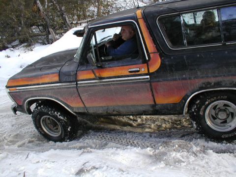 1979 Ford Bronco II - A man drives a vintage Ford Bronco through a snowy, wooded area.