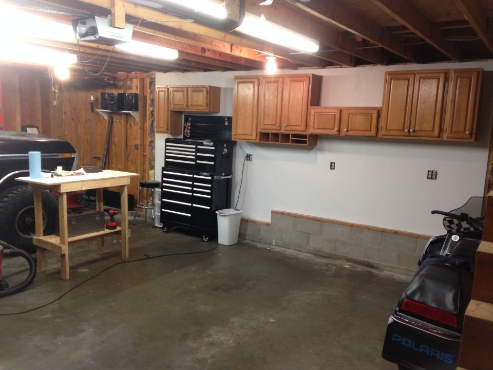 Black pickup truck and snowmobile in a garage with tool chests and cabinets