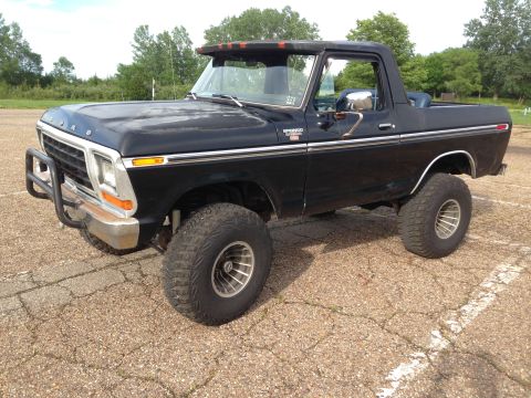 1979 Ford Bronco - This black 1978 Ford Bronco features a bull bar and lifted suspension, seen from a front three-quarter perspective.