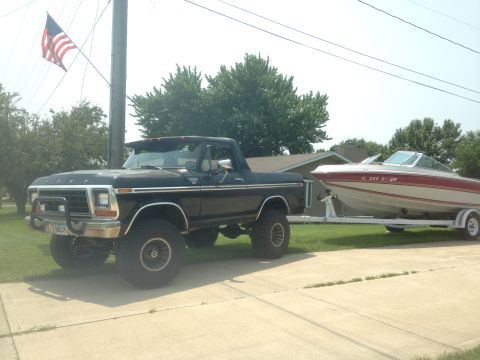 1979 Ford Bronco - Black 1979 Ford F-Series pickup truck is seen towing a boat on a trailer.