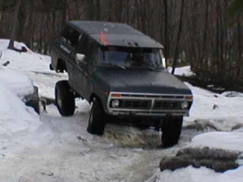 1979 Ford Bronco II - A lifted dark gray Ford Bronco navigates a snowy, rocky terrain.