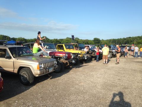 1979 Ford Bronco - A group of Jeeps are gathered together on a sunny day with people socializing.