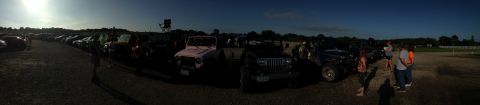 1979 Ford Bronco - A wide shot captures a gathering of vehicles, including several Jeeps, parked under a darkening sky.
