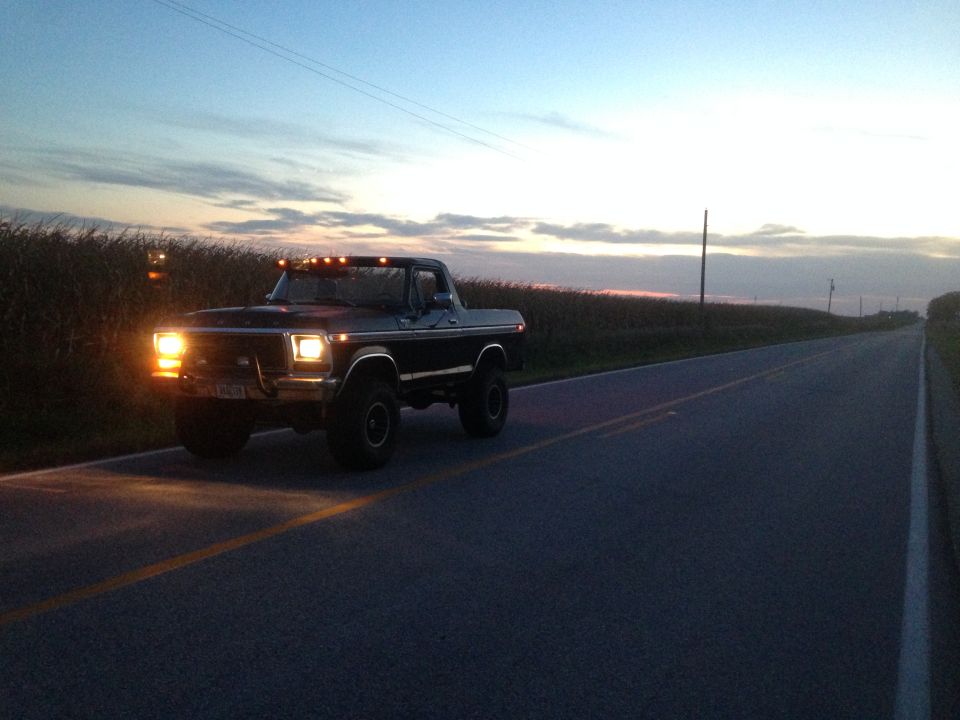 1979 Ford Bronco driving on a rural road at dusk