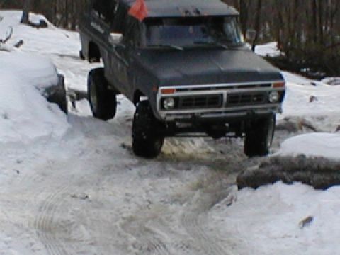 1979 Ford Bronco II - This lifted, dark-colored SUV navigates a snowy and rocky path, with its grille design hinting at a 1979 model year.