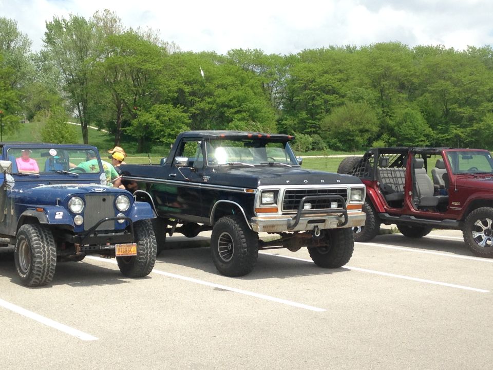 Black Ford pickup truck parked next to two Jeeps