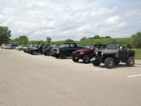 1979 Ford Bronco - Several off-road vehicles are parked in a lot on a cloudy day.