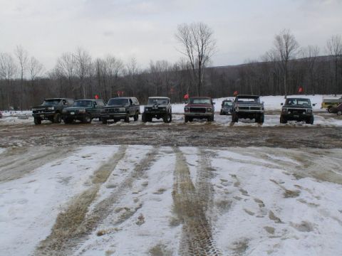 1979 Ford Bronco II - Multiple SUVs and trucks are parked in a snowy lot during what appears to be an off-road event.