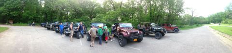 1979 Ford Bronco - A group of Jeeps are parked in a lot, with several people interacting around the vehicles.