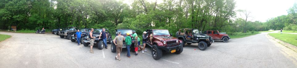 Several Jeeps parked in a line, some with people gathered around them