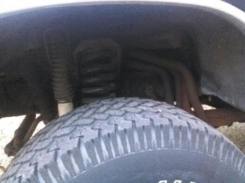 1979 Ford Bronco - This image shows a close-up view of a vehicle's front tire and suspension components within the wheel well.
