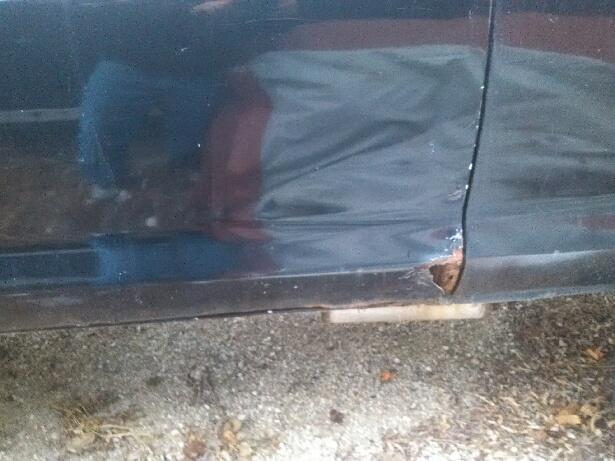 Dark vehicle door and rocker panel with visible rust on the lower edge