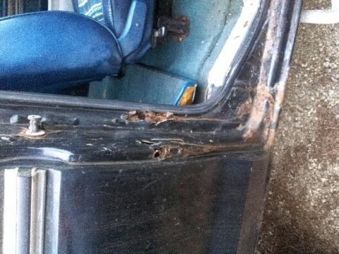 1979 Ford Bronco - Close-up of a rusted interior door frame and blue seat, indicating wear and tear.