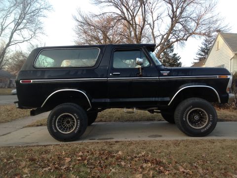 1979 Ford Bronco - Side profile of a black 1979 Ford Bronco with aftermarket wheels and chrome trim.