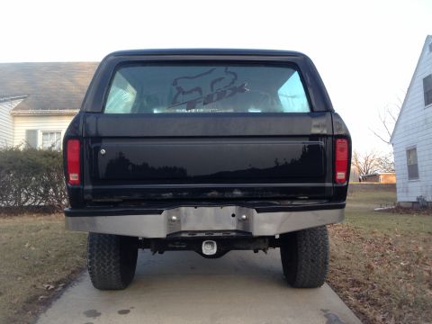 1979 Ford Bronco - The rear of a black SUV is shown parked in a driveway with houses on either side.