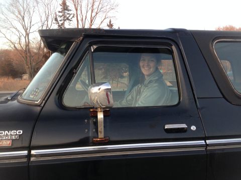 1979 Ford Bronco - Woman smiles from the driver's seat of a black 1979 Ford Bronco.