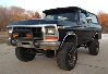 1979 Ford Bronco - This black 1979 Ford Bronco is shown from a 3/4 front view, large tires and aftermarket lighting.