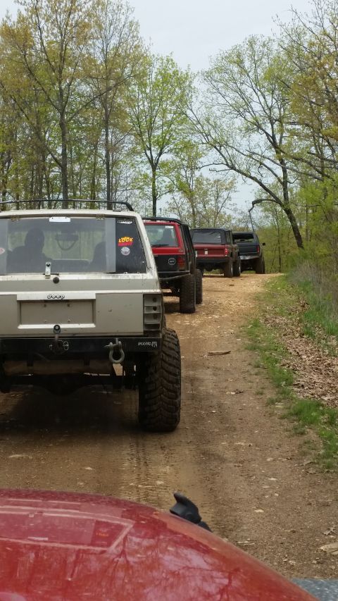1979 Ford Bronco - A convoy of off-road vehicles navigates a wooded trail on a dirt road.
