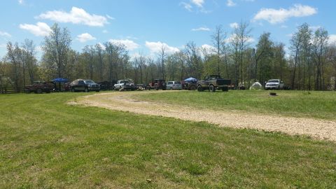1979 Ford Bronco - Several vehicles are gathered in a field under a clear blue sky.