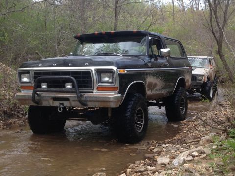 1979 Ford Bronco - A black 1978 Ford Bronco navigates a shallow stream, followed by another off-road vehicle.