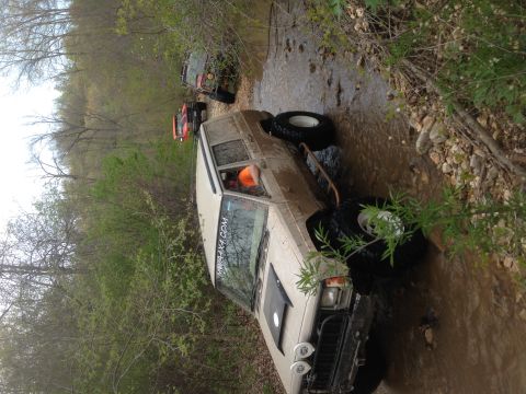 1979 Ford Bronco - Multiple off-road vehicles, including a Jeep Cherokee XJ, are seen traversing a rocky stream bed.