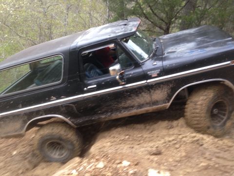 1979 Ford Bronco - This black Ford Bronco is tackling a challenging off-road trail.