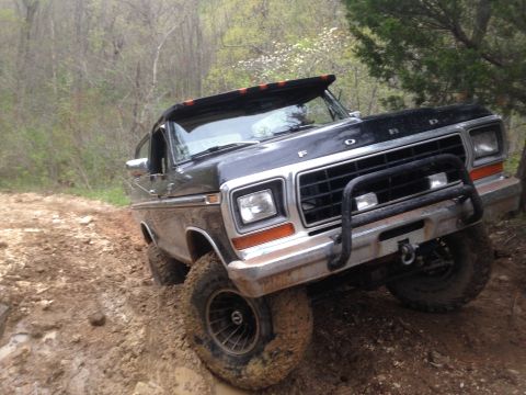 1979 Ford Bronco - This Ford Bronco is navigating a rough, unpaved road in a wooded area.