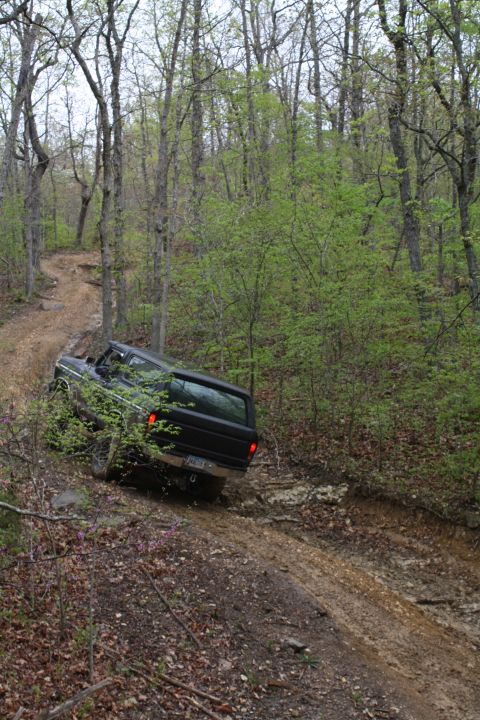 1979 Ford Bronco - A black Ford Bronco navigates a muddy, wooded trail during an off-road excursion.