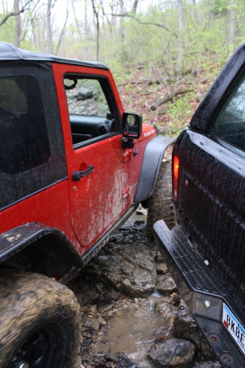 1979 Ford Bronco - Two off-road vehicles are shown navigating a challenging muddy and rocky trail.