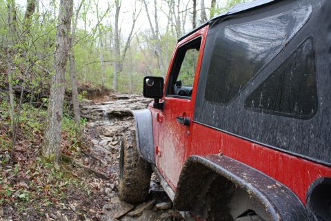 1979 Ford Bronco - A red Jeep Wrangler navigates a challenging, rocky off-road trail.