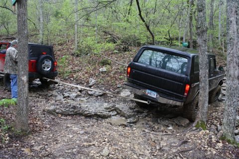 1979 Ford Bronco - A black 1978 Ford Bronco is stuck on a rough trail, being pulled by a red Jeep.